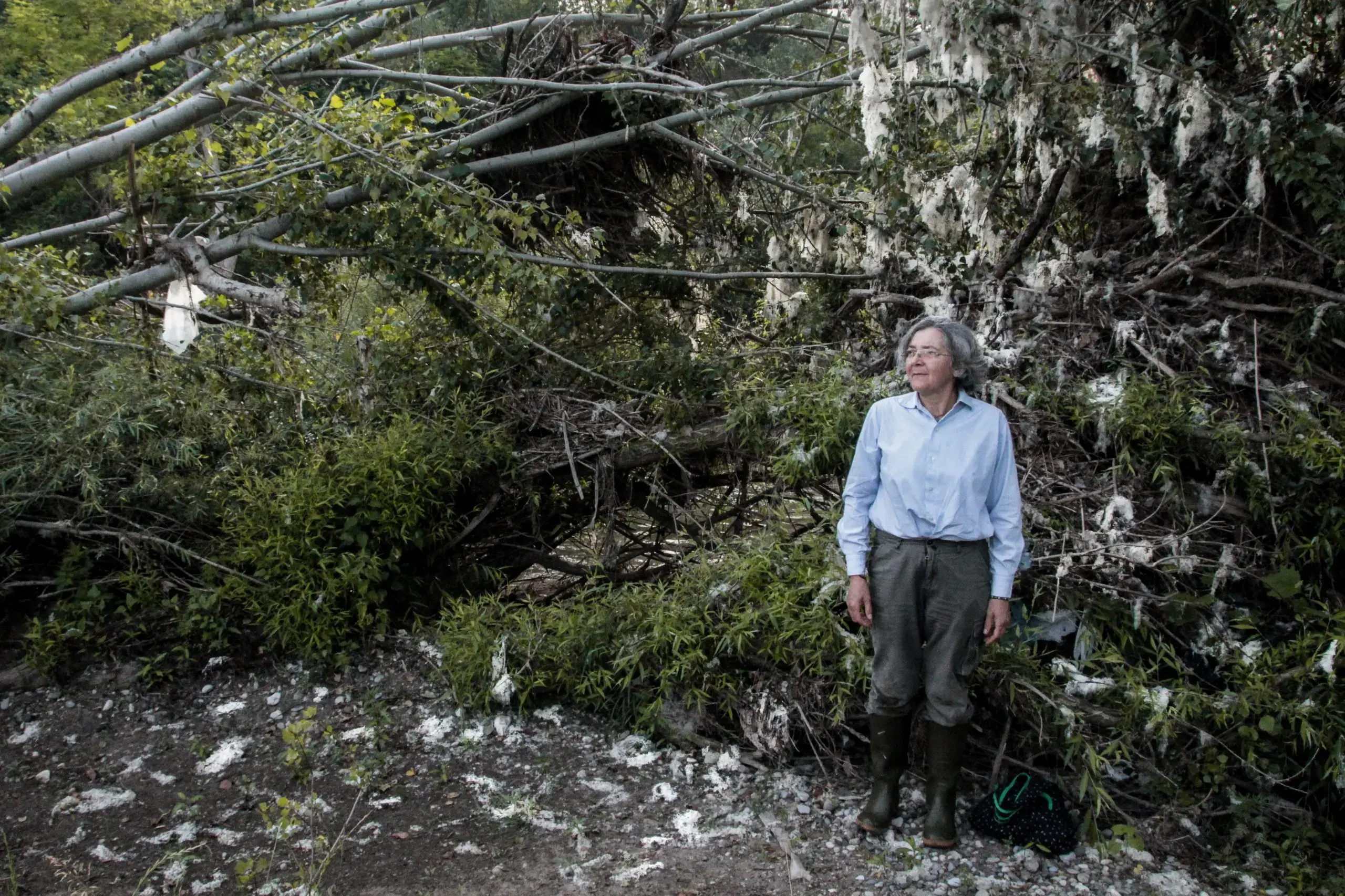 Anna, vive da vent’anni in simbiosi col fiume, trascorrendo quasi tutte le proprie giornate vicino al Chiese. Alle sue spalle i resti di sacchetti di plastica portati dalla corrente quando il fiume è in piena.
